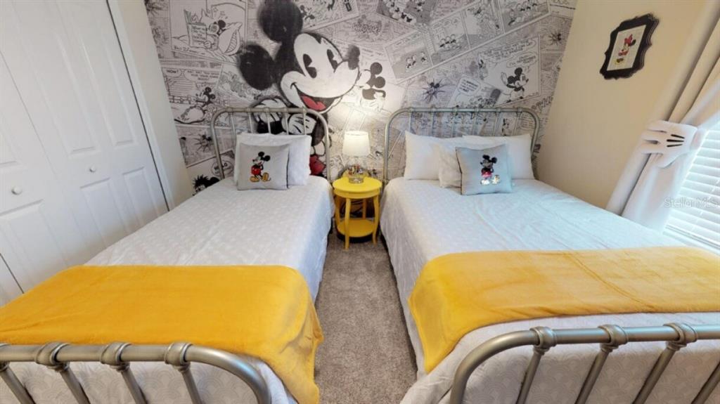 A bedroom features two twin beds with yellow blankets and Mickey Mouse-themed wallpaper — 4968 WINDERMERE AVENUE, KISSIMMEE, FL