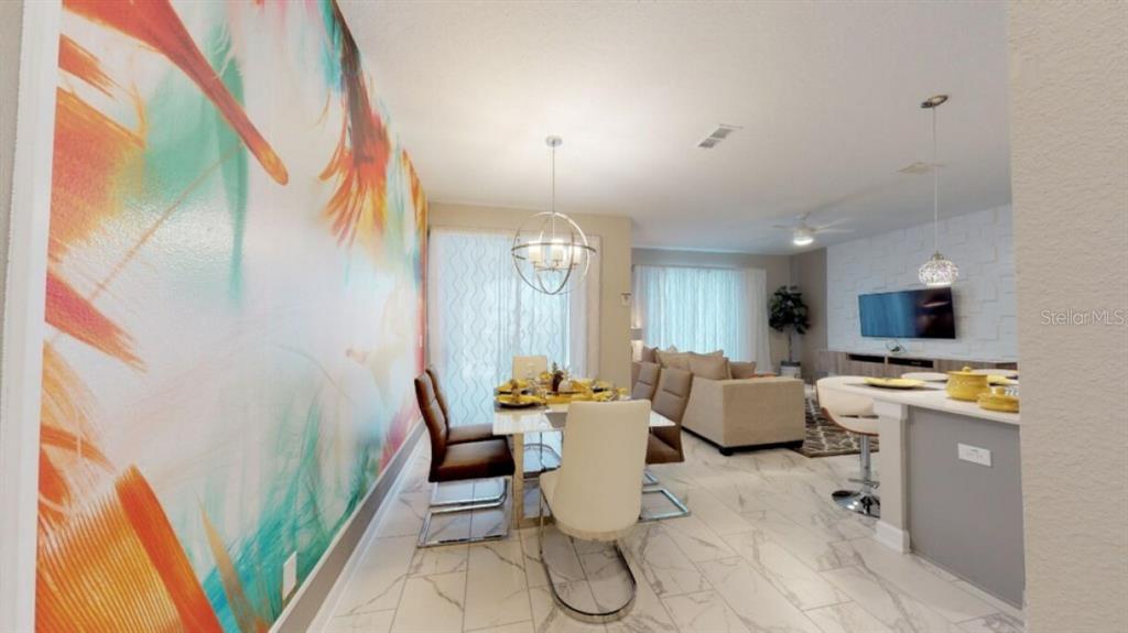 An open-concept dining and living area features a colorful accent wall and marble-look tile flooring — 4968 WINDERMERE AVENUE, KISSIMMEE, FL