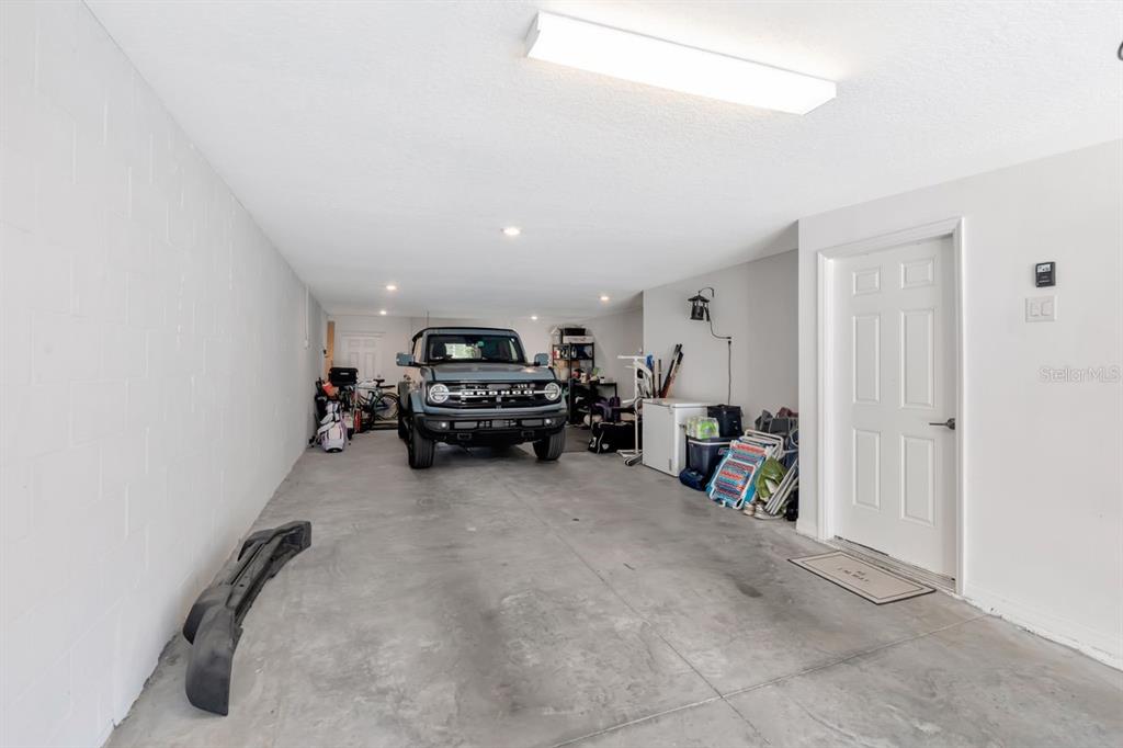 A garage with a concrete floor, a parked Ford Bronco, and a white door — 4551 TUSCAN LOON DRIVE, TAMPA, FL