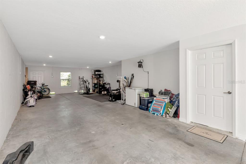 A spacious garage with concrete floors, white walls, and a white door — 4551 TUSCAN LOON DRIVE, TAMPA, FL