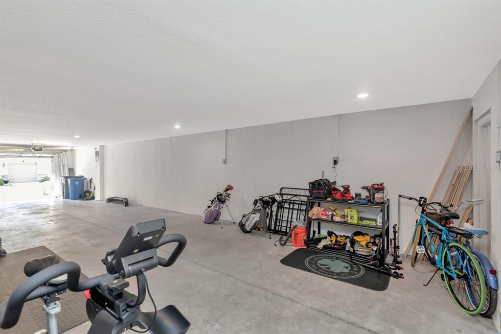 A spacious, unfinished garage with concrete floors, white block walls, and various stored items — 4551 TUSCAN LOON DRIVE, TAMPA, FL