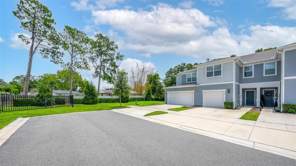 A two-story townhouse with a gray exterior, two garage doors, and a paved driveway — 2033 CANNY COVE, WINTER PARK, FL