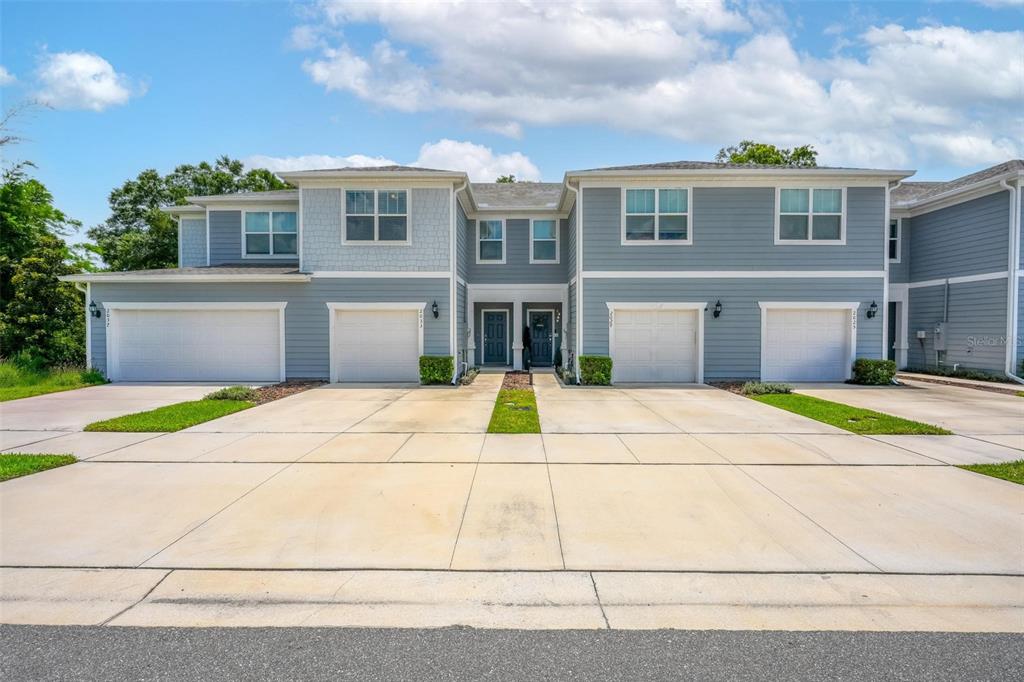 A two-story townhouse complex with four garage bays and a shared concrete driveway — 2033 CANNY COVE, WINTER PARK, FL