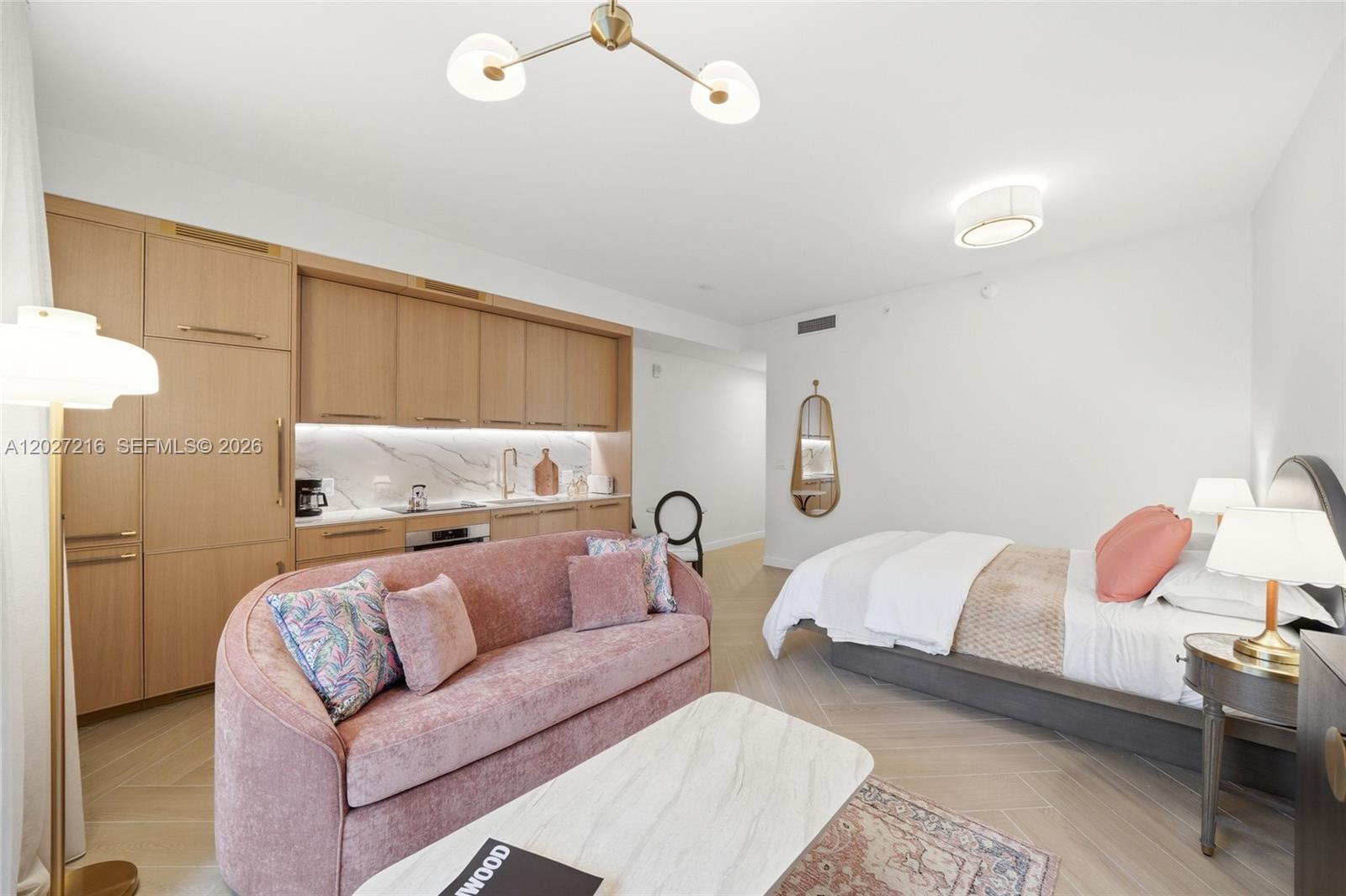 A studio apartment features a kitchenette with wood cabinetry, a pink sofa, and a bed — 2700 NW 2nd Ave # 345, Miami FL 33127, MIAMI, FL