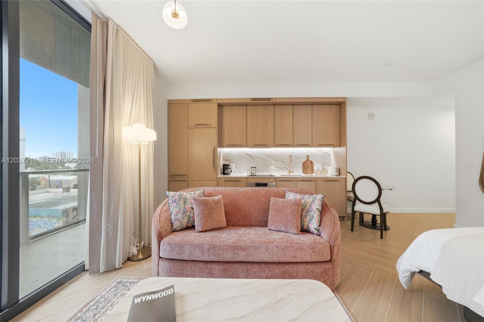 A studio apartment features a pink sofa, light wood cabinetry, and a balcony with city views — 2700 NW 2nd Ave # 345, Miami FL 33127, MIAMI, FL