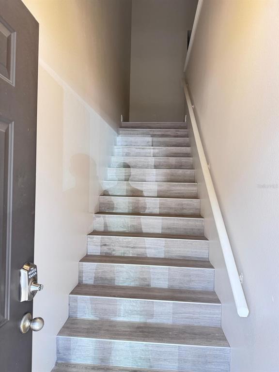 A staircase with wood-look flooring and a white handrail leads upward from a doorway — 5555 BAYWATER DRIVE, TAMPA, FL