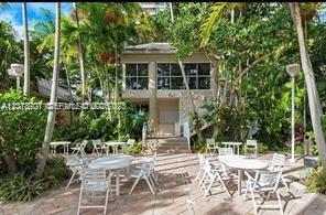 An outdoor patio with white tables and chairs sits in front of a two-story building — 770 NE 69th St # 1E, Miami FL 33138, MIAMI, FL