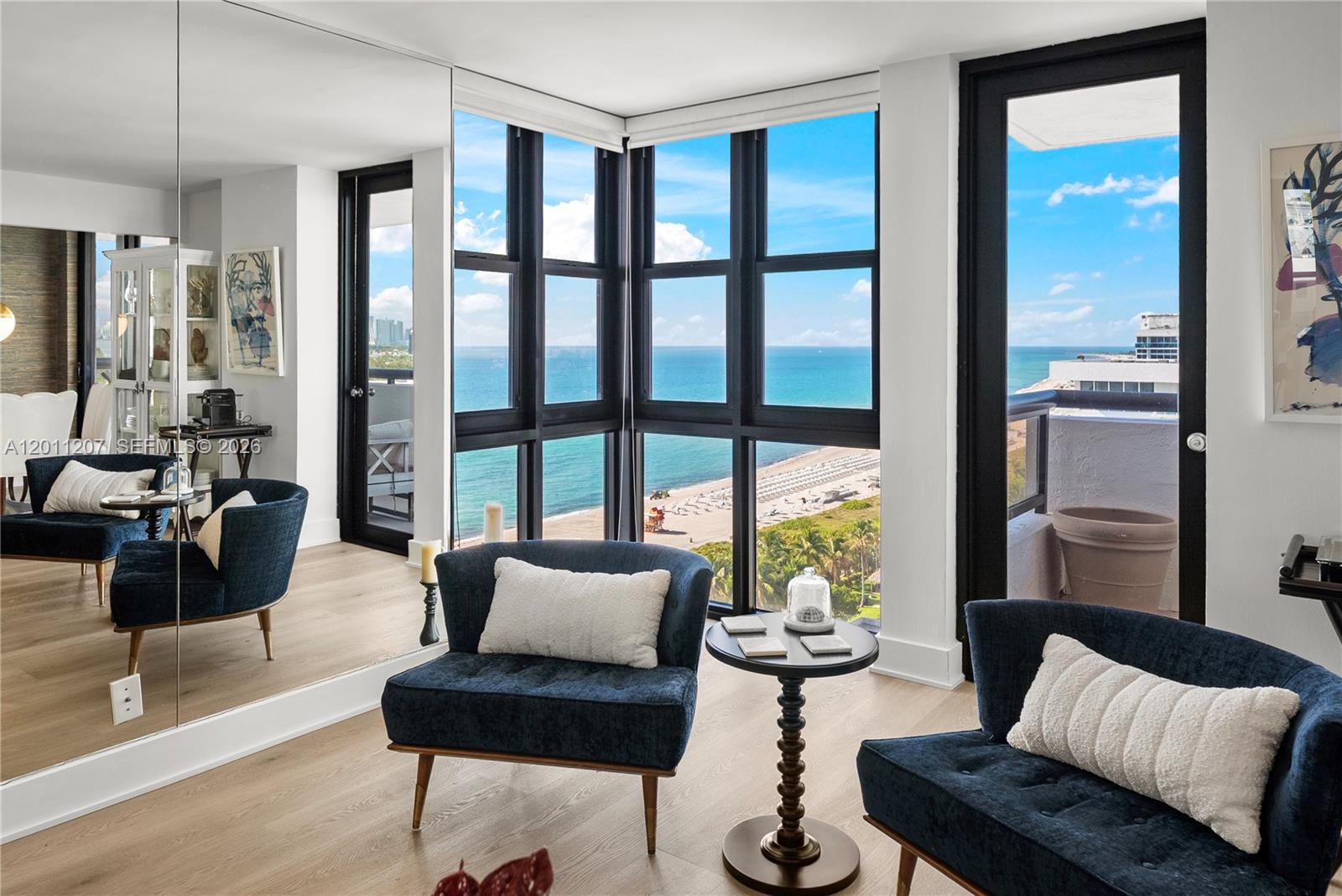 A room with blue armchairs, a small table, and floor-to-ceiling windows overlooking the ocean — 2555 Collins Ave # 2014, Miami Beach FL 33140, MIAMI BEACH, FL
