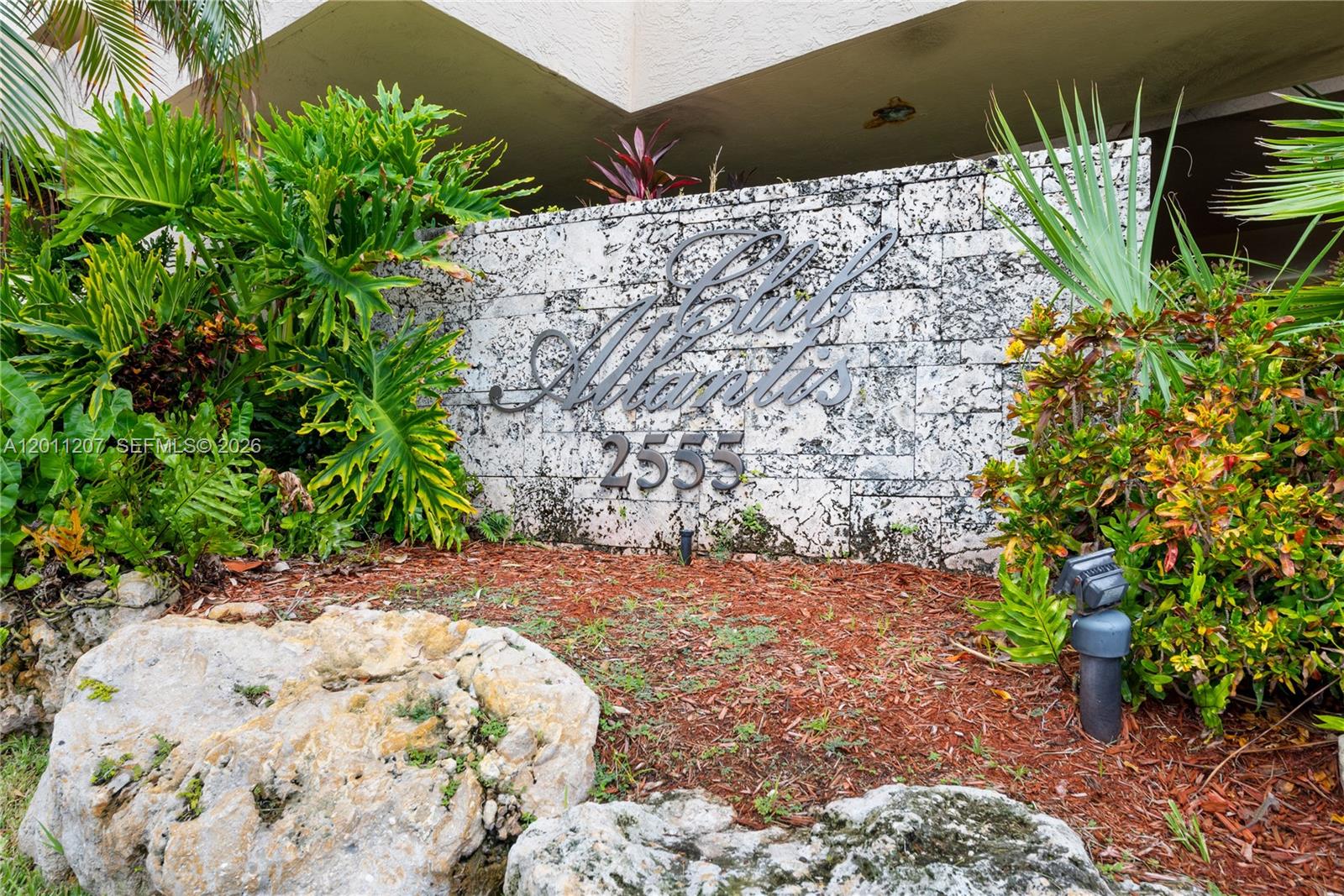 A stone wall displays the name Club Atlantis and the number 2555 amidst tropical landscaping — 2555 Collins Ave # 2014, Miami Beach FL 33140, MIAMI BEACH, FL