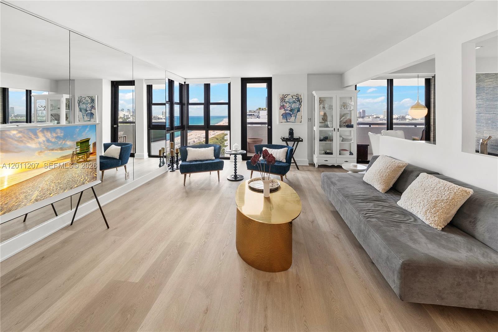 A bright living room features light wood floors, a gold coffee table, and ocean views — 2555 Collins Ave # 2014, Miami Beach FL 33140, MIAMI BEACH, FL