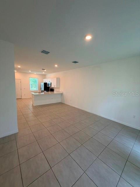 An open-concept kitchen with white cabinets and a breakfast bar overlooks a tiled living area — 3188 SKYLINE LOOP, KISSIMMEE, FL