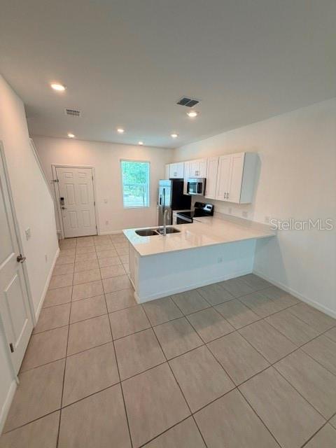 A kitchen features white cabinets, a quartz island, and tile flooring in an open space — 3188 SKYLINE LOOP, KISSIMMEE, FL