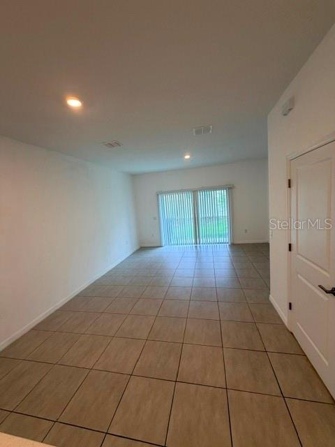 An empty room features light-colored tile flooring, recessed lighting, and sliding glass doors — 3188 SKYLINE LOOP, KISSIMMEE, FL