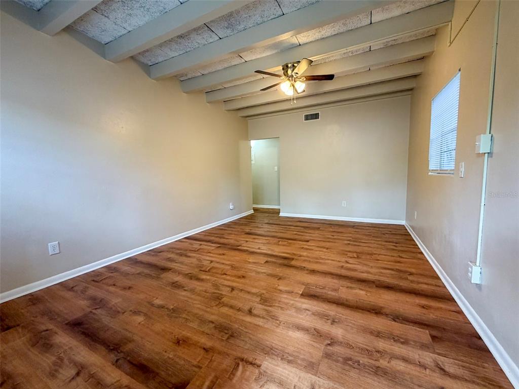 A small, yellow, single-story building with a white door and metal awning sits outdoors — 219 NW 3RD AVENUE UNIT B, GAINESVILLE, FL