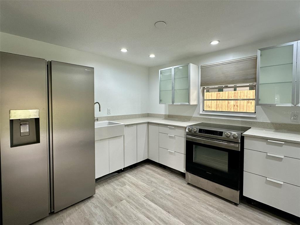 A modern kitchen features white cabinets, stainless steel appliances, and light wood-look flooring — 502 E KNOLLWOOD STREET, TAMPA, FL