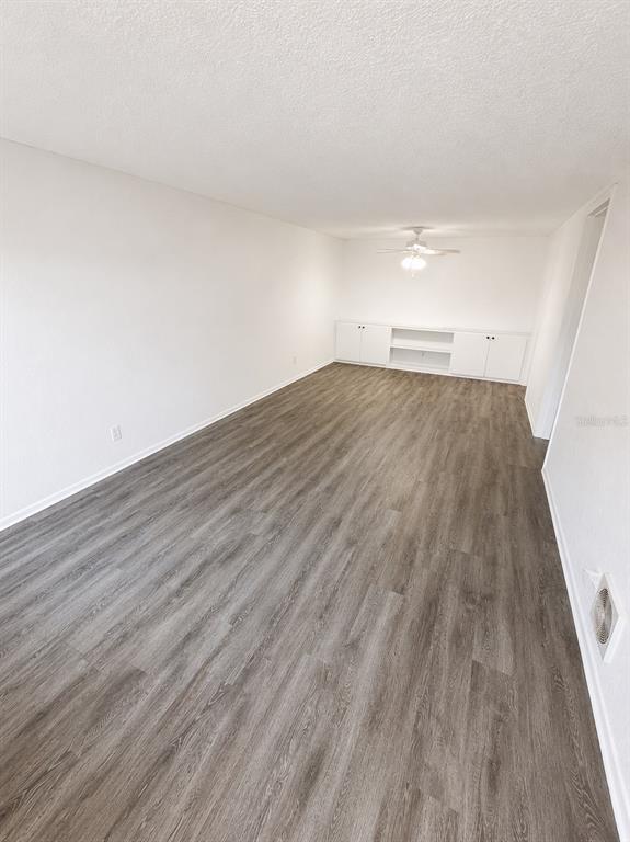 An empty room features white walls, gray wood-look flooring, and a built-in white cabinet unit — 420-420 MILLS STREET UNIT 32, LEESBURG, FL