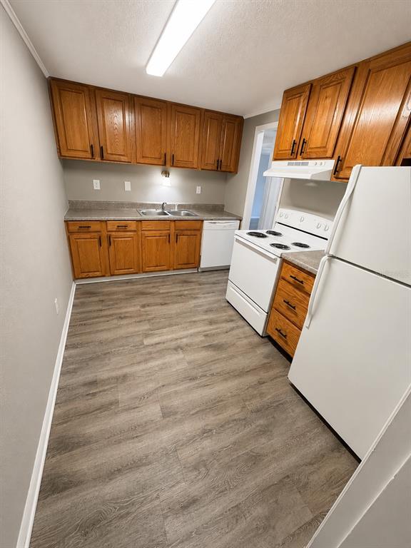 A kitchen features wood cabinets, white appliances, gray flooring, and a double-basin sink — 420-420 MILLS STREET UNIT 32, LEESBURG, FL