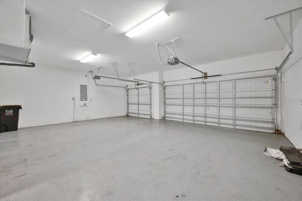 An empty two-car garage with white walls, a concrete floor, and two overhead doors — 2850 SHELDON STREET, LAKELAND, FL