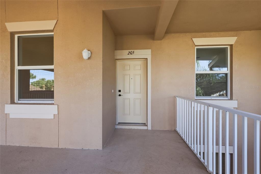 An exterior view of a building entrance with a white door numbered 205 — 803 FAIRWAYCOVE LANE UNIT 205, BRADENTON, FL