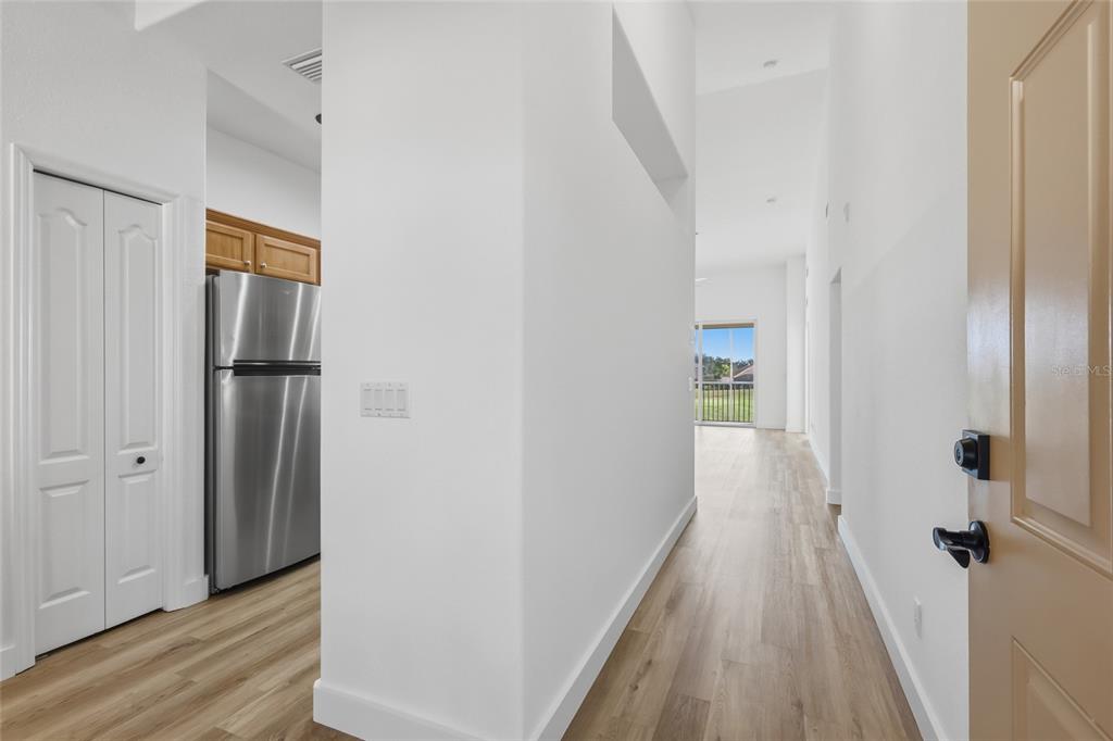 A view from an entryway looking down a hallway toward a sliding glass door — 803 FAIRWAYCOVE LANE UNIT 205, BRADENTON, FL