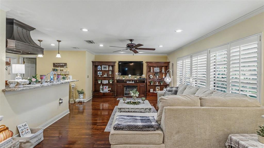 A living room with dark wood floors, a fireplace, built-in shelves, and a sectional sofa — 121 SHADOW LANE, LAKELAND, FL