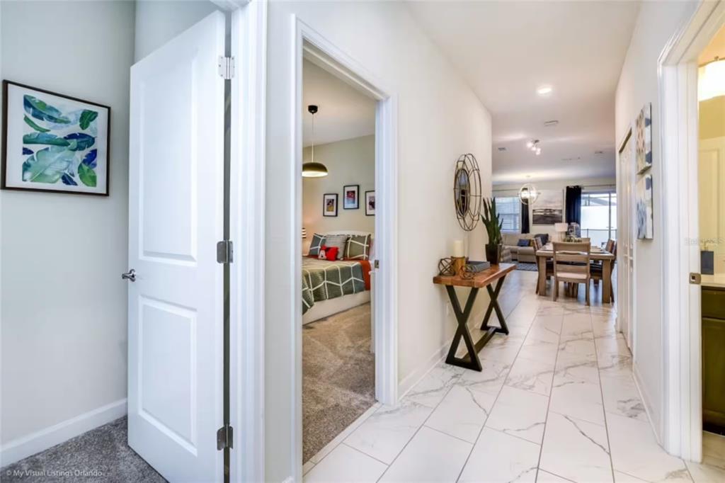 A hallway with white tile flooring leads to an open-concept living and dining area — 4811 LULLABY LANE, KISSIMMEE, FL