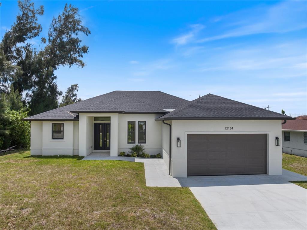 A single-story house with white stucco walls, a dark roof, and a two-car garage — 12134 MALLORCA AVENUE, NORTH PORT, FL