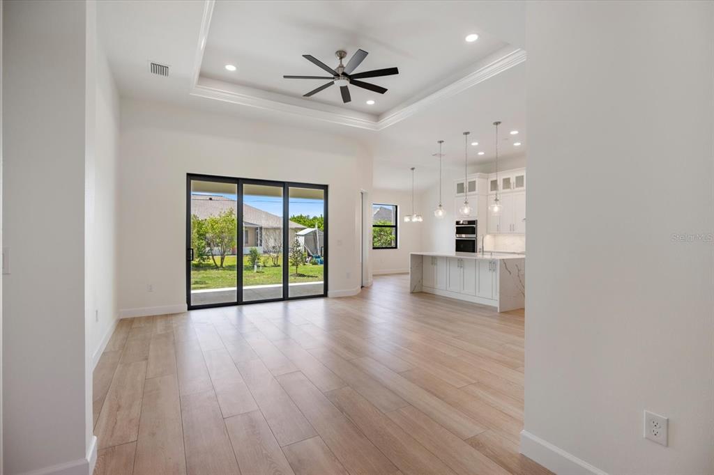 An open-concept living area features light wood floors, a tray ceiling, and a modern kitchen — 12134 MALLORCA AVENUE, NORTH PORT, FL