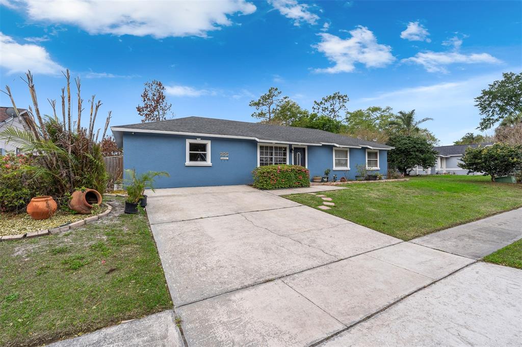 A blue, single-story house features a concrete driveway and a front lawn — 8509 LYONIA DRIVE, ORLANDO, FL