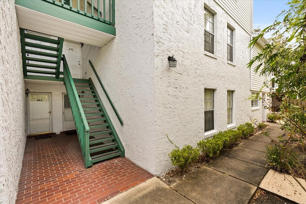 An exterior view of a two-story building with white stucco walls and green wooden stairs — 494 W PAR STREET, ORLANDO, FL