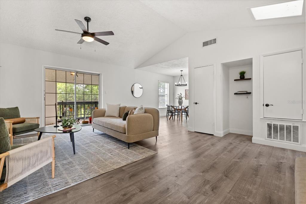 A living room with wood-look flooring, a beige sofa, and a sliding glass door — 494 W PAR STREET, ORLANDO, FL