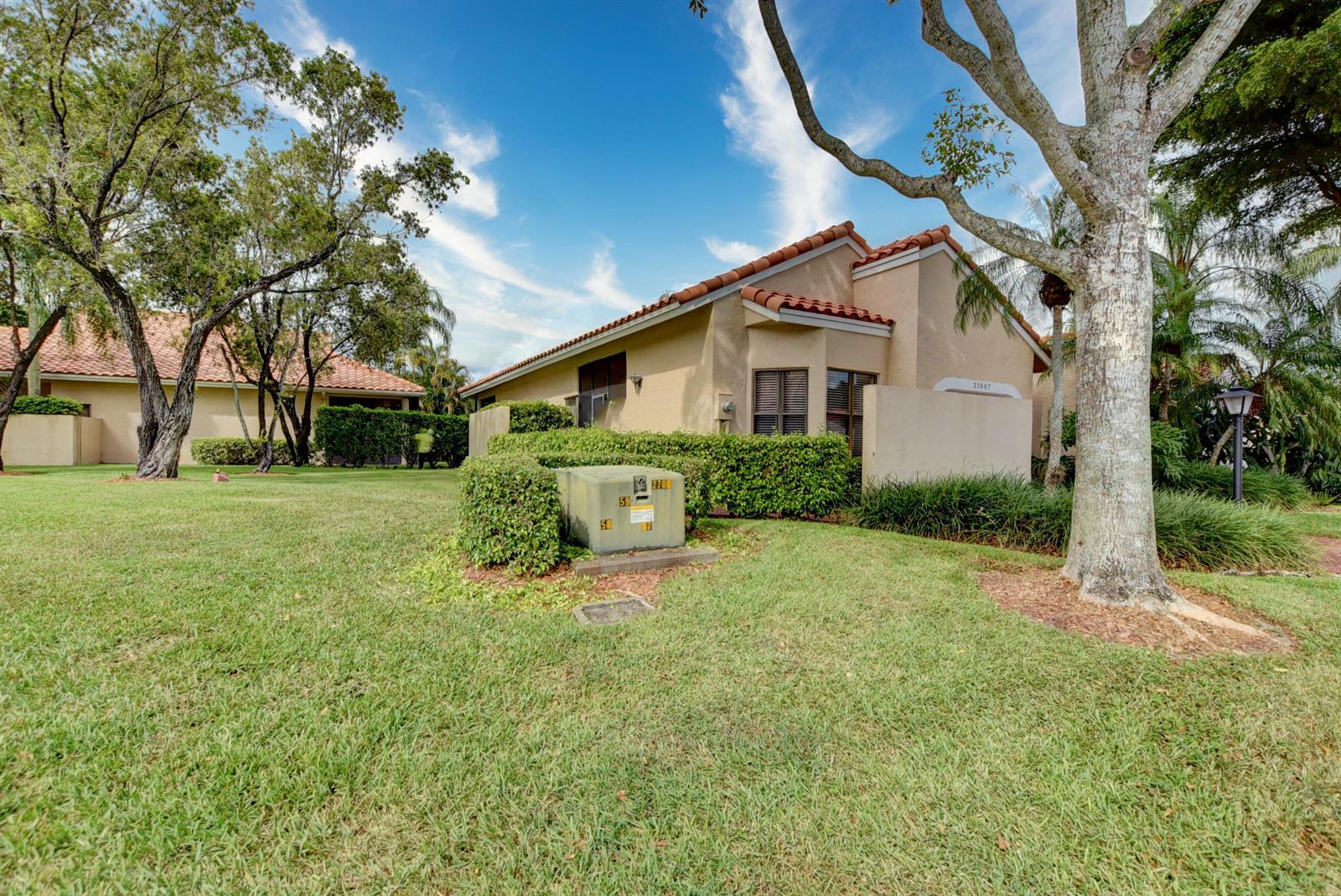 A beige single-story house with a tile roof sits behind a green electrical transformer box — 22667 Meridiana Drive, Boca Raton FL 33433, BOCA RATON, FL