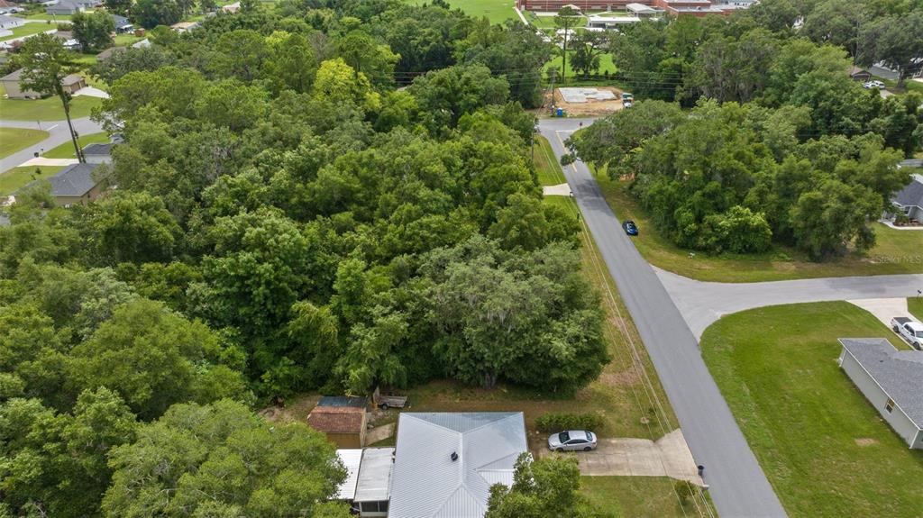 An aerial view shows a house with a metal roof surrounded by dense trees — SW 131ST PL ROAD, OCALA, FL