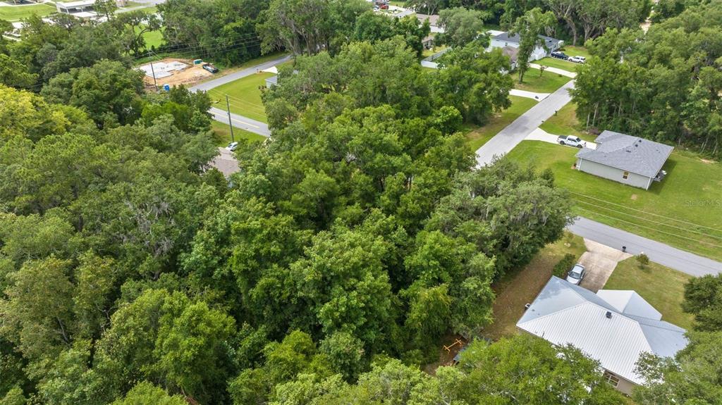 An aerial view shows a wooded lot situated between residential streets and houses — SW 131ST PL ROAD, OCALA, FL