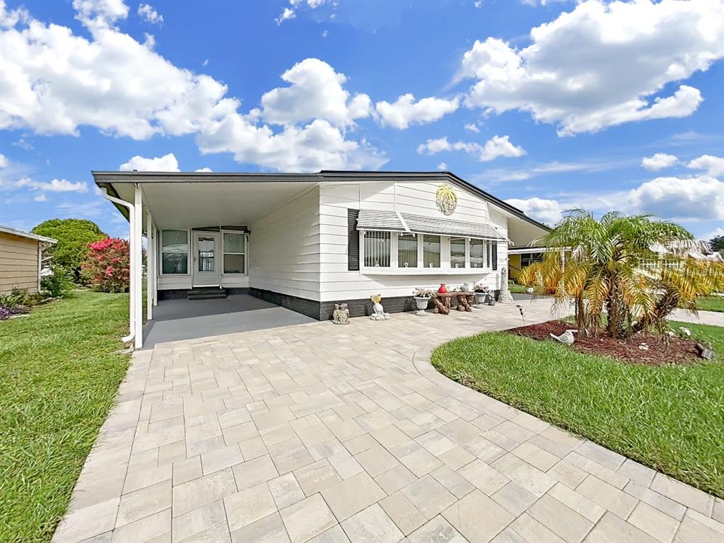 A white mobile home features a paved driveway, a carport, and a front lawn — 5022 FOXWOOD BLVD, LAKELAND, FL