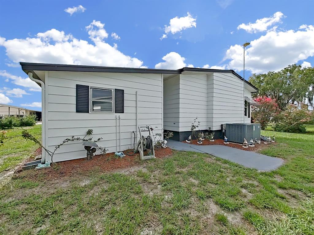 The exterior of a white mobile home features horizontal siding, black shutters, and an AC unit — 5022 FOXWOOD BLVD, LAKELAND, FL