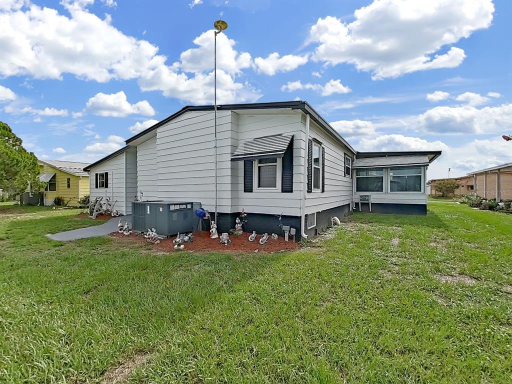 The exterior of a white manufactured home features a tall antenna and a central air unit — 5022 FOXWOOD BLVD, LAKELAND, FL