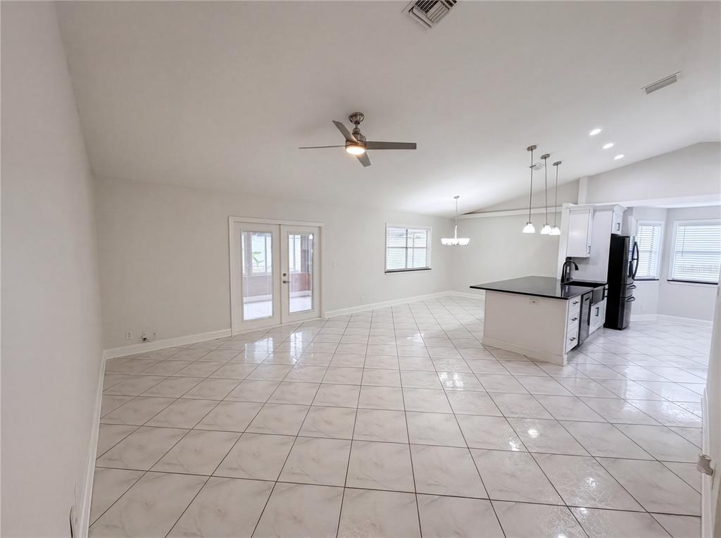 An open-concept room features white tiled floors, a kitchen island, and a ceiling fan — 4614 ZOLTAN DRIVE, TITUSVILLE, FL