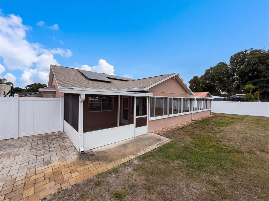 The rear exterior of a house features a screened-in porch, a paver patio, and a yard — 4614 ZOLTAN DRIVE, TITUSVILLE, FL