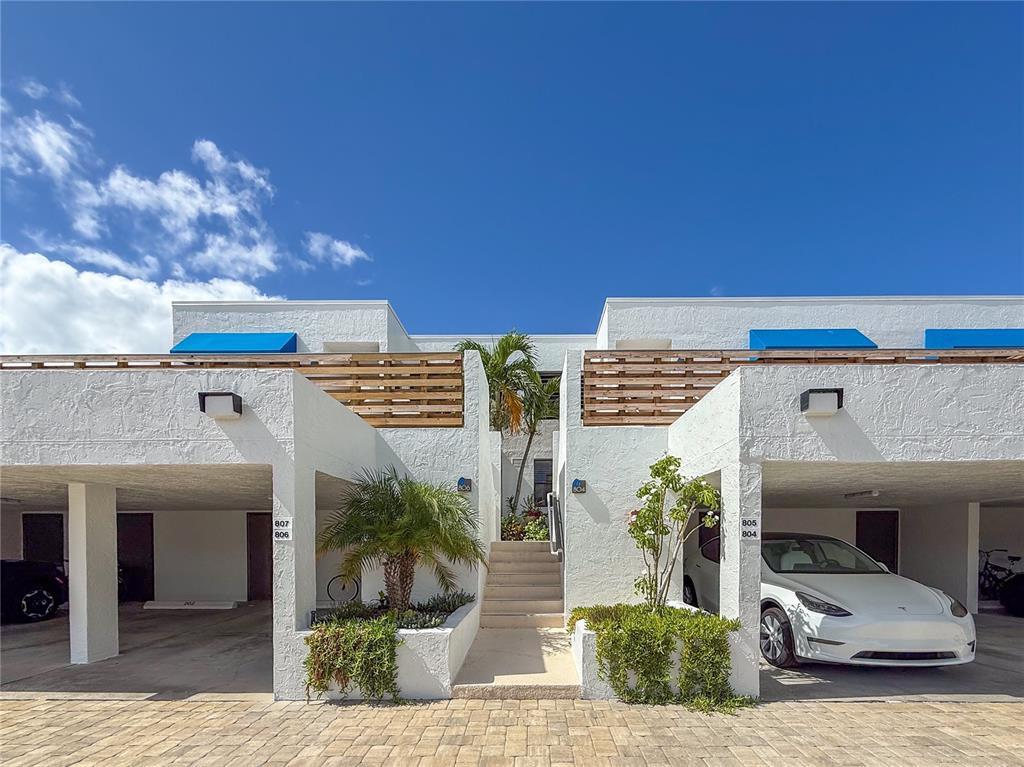 A white two-story building features covered parking spaces and a central staircase leading upstairs — 806 BAYPORT WAY UNIT 806, LONGBOAT KEY, FL
