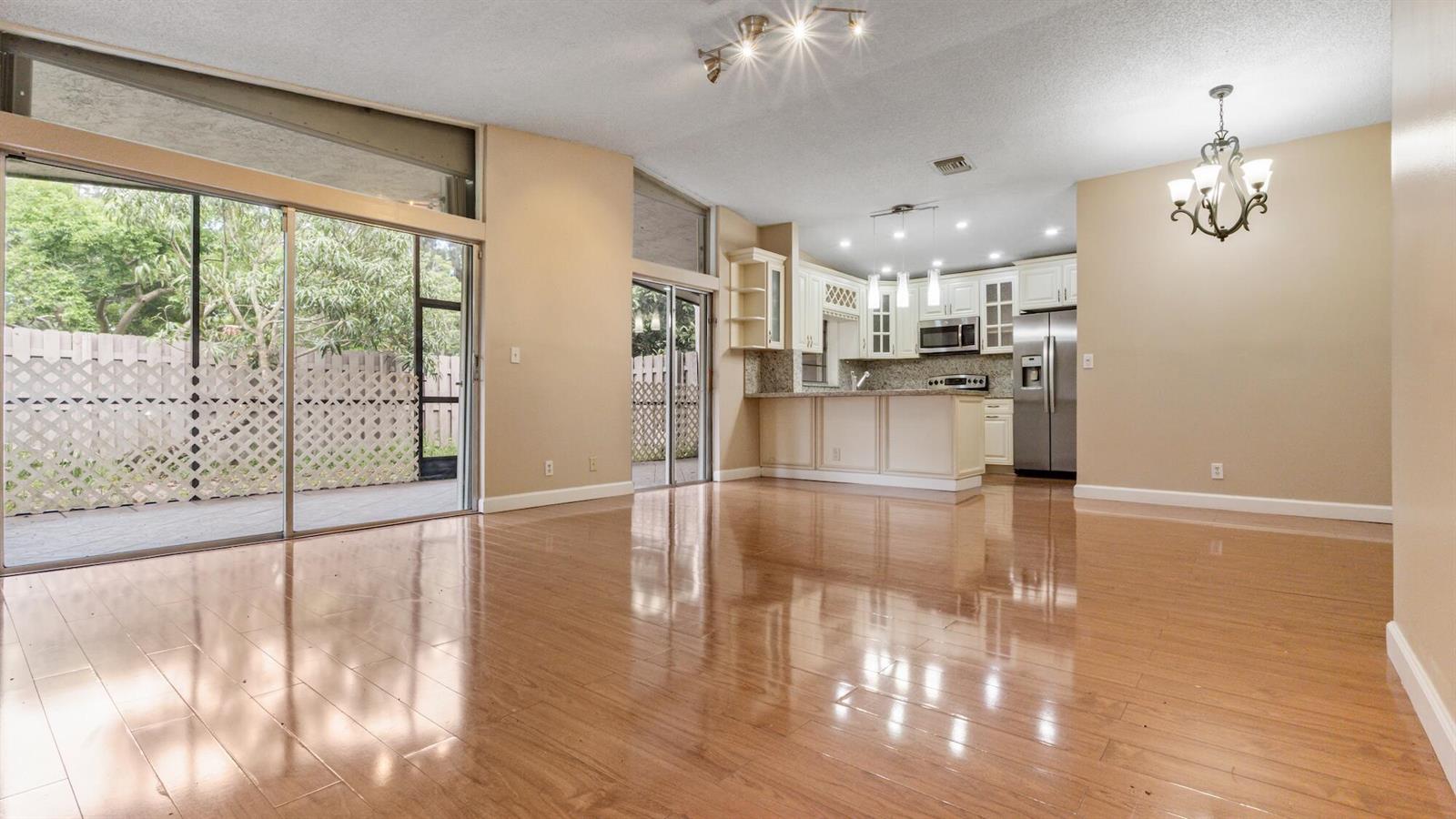 A bright living area with hardwood floors opens to a kitchen and a screened patio — 570 Woodgate Circle # A, Sunrise FL 33326, SUNRISE, FL