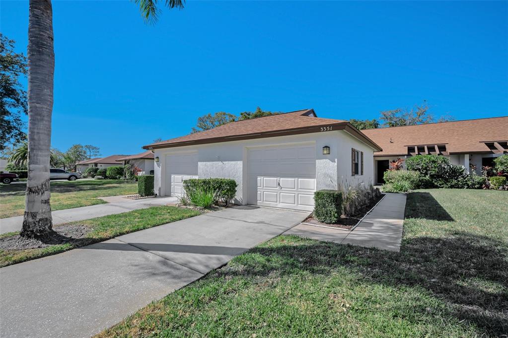 A white single-story duplex with two garage doors and a brown shingled roof — 3351 LORI LANE UNIT 3351, NEW PORT RICHEY, FL