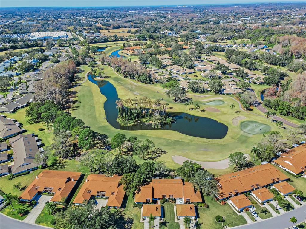 An aerial view shows a golf course fairway with a central pond surrounded by residential buildings — 3351 LORI LANE UNIT 3351, NEW PORT RICHEY, FL