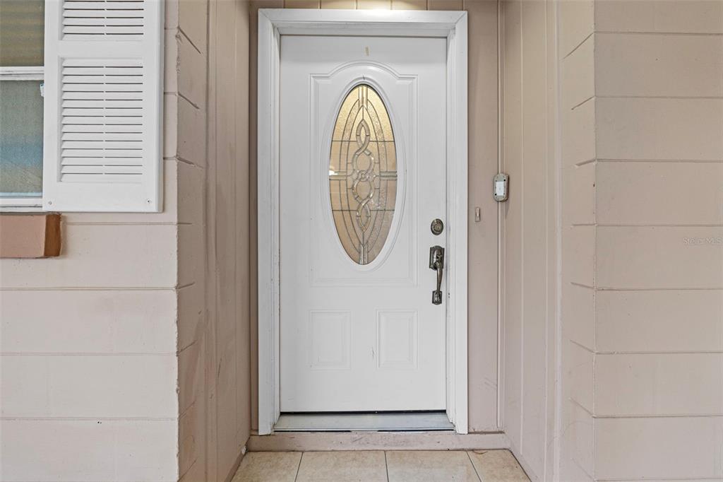 A white front door with an oval glass insert is set within a beige wall — 912 AVENUE T SE, WINTER HAVEN, FL