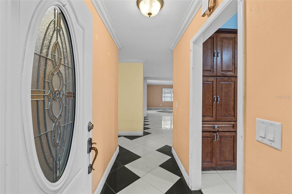 An entryway features a white door with a decorative glass insert and black-and-white tiled flooring — 912 AVENUE T SE, WINTER HAVEN, FL