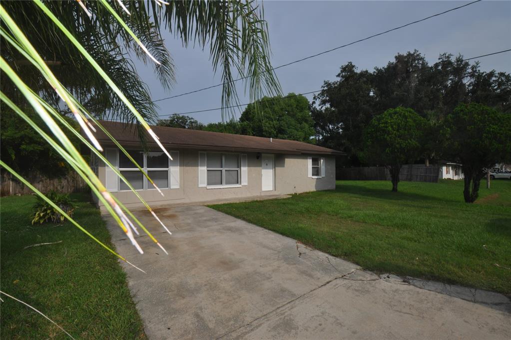A single-story house with a concrete driveway, a brown roof, and a large front lawn — 1624 MERRICK ROAD, LAKELAND, FL