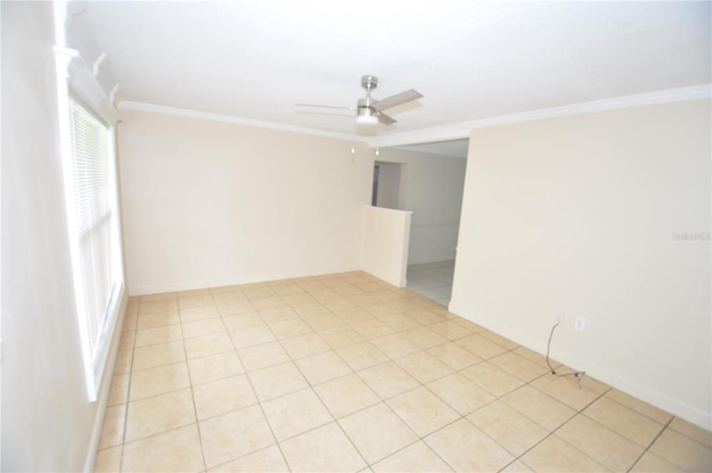 An empty room features beige tile flooring, white walls, and a ceiling fan — 1624 MERRICK ROAD, LAKELAND, FL