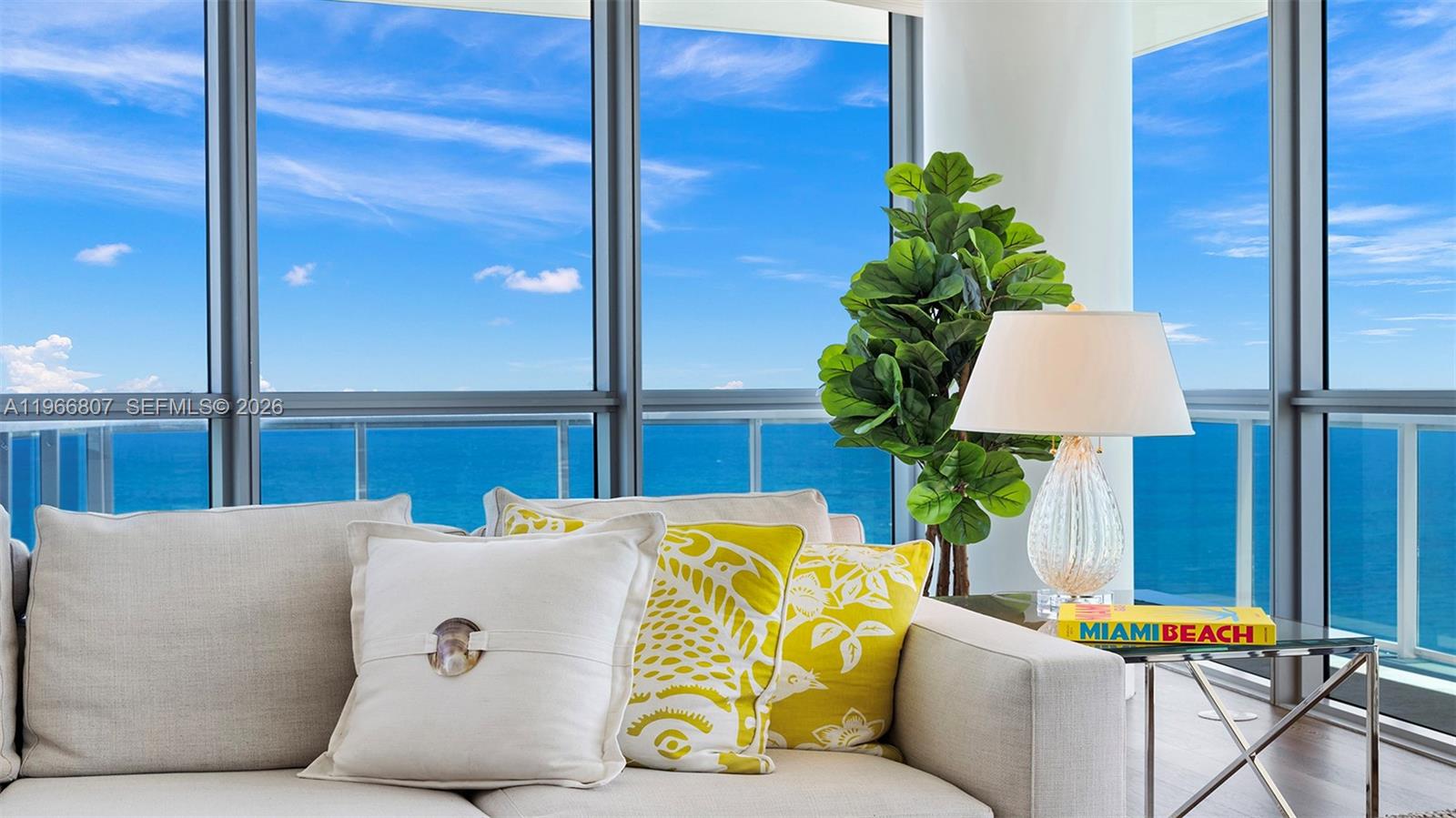 A living room features a beige sofa, a decorative lamp, and floor-to-ceiling windows overlooking the ocean — 101 20th St # 3909, Miami Beach FL 33139, MIAMI BEACH, FL