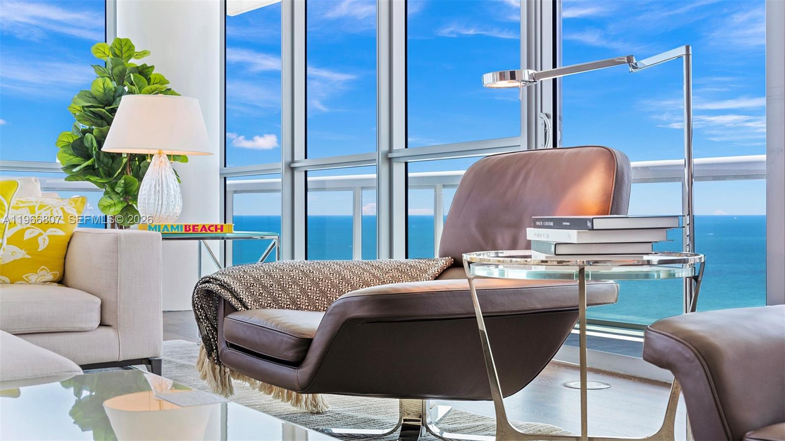 A modern living room features a leather armchair, glass side table, and floor-to-ceiling ocean views — 101 20th St # 3909, Miami Beach FL 33139, MIAMI BEACH, FL