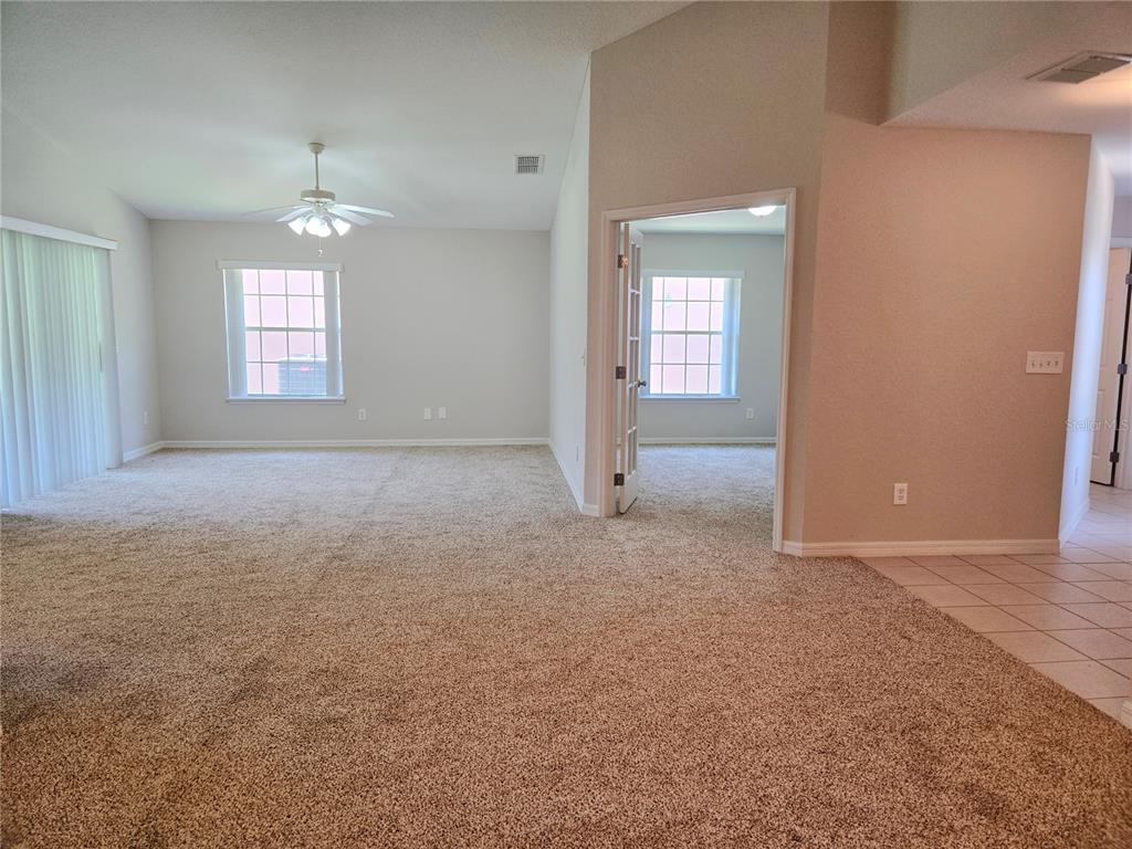 A carpeted living room features a ceiling fan, sliding glass doors, and French doors — 17974 SE 115TH CIRCLE, SUMMERFIELD, FL